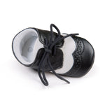 Black leather baby shoes with white soles on a white background