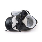 Black and white baby shoes with black laces on a white background