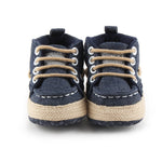 Pair of navy blue baby shoes with beige soles on a white background