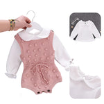 Baby outfit with pink knitted romper and white shirt on a hanger against a gray background.