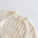 Close-up of a cream-colored knitted sweater on a light gray background