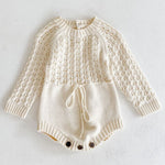 Cream-colored knitted baby romper with long sleeves on a light gray background