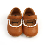 Pair of brown baby shoes with a strap on a white background