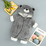 Gray bear-themed baby onesie on a gray background with a magazine and flowers.