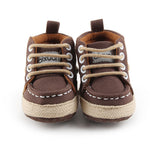 Pair of brown baby shoes with white laces on a white background