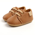 Pair of brown leather baby shoes on a white background