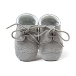 Pair of gray baby shoes with laces on a white background
