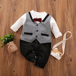 Children's formal outfit with vest, shirt, and bow tie on a wooden surface.