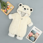 White bear-themed baby snowsuit on a gray background with a magazine and flowers.