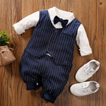 Baby outfit with navy pinstripe romper, white shirt, bow tie, and white shoes on a wooden surface.