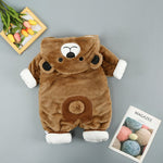 Brown plush toy with white paws and a face on a gray surface next to a magazine.