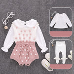 Baby outfit set with pink romper and white long-sleeve top on a gray background