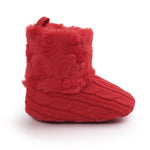 Red knitted baby boot with fluffy top on a white background
