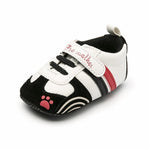 Black, white, and red baby shoe with paw print design on a white background
