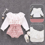 Baby outfit with white top and pink polka dot romper on a gray background