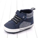Navy blue children's shoe with white sole on a light wooden floor