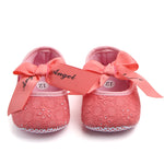 Pink baby shoes with ribbons and 'Angel' text on a white background