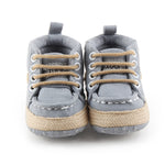 Pair of gray baby shoes with brown laces on a white background