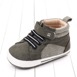 Gray baby shoe with white sole on a light wooden floor