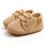 Pair of beige children's shoes with soft sole on a white background