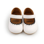 Pair of white baby shoes with brown soles on a white background