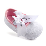 Pink baby shoe with white lace and bow on a white background