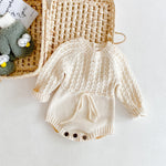 Baby romper with cable knit pattern on a light background