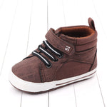 Brown baby shoe with black and white laces on a light wooden floor